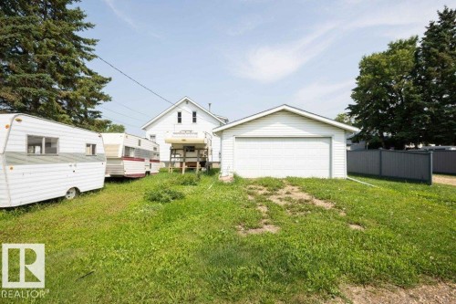 Detached garage featuring a white overhead door and white siding - 10940 100A Ave, Westlock, AB - Outdoor