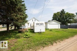 White vinyl-sided home with a detached garage and a grass yard - 