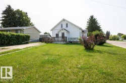 Expansive front yard with a large grassy area, mature shrubbery, and a paved driveway - 