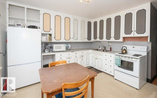 Kitchen with white cabinetry, white appliances, and a double basin sink - 10940 100A Ave, Westlock, AB - Indoor Photo Showing Kitchen With Double Sink