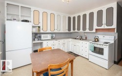 Kitchen with white cabinetry, white appliances, and a double basin sink - 