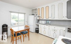 Kitchen featuring a window overlooking exterior surroundings, upper and lower cabinetry, a double basin sink, and a refrigerator - 