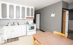 Kitchen featuring white cabinetry with dark trim, a double basin stainless steel sink, and a freestanding white range - 