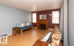 Living area featuring wood-finish flooring, a traditional fireplace with a wood mantel, and multiple windows providing natural light - 