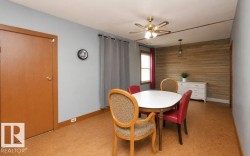 Spacious room featuring wood-finish flooring, a full wall with horizontal wood paneling, and a ceiling fan with integrated lighting - 