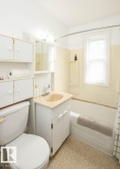 Bathroom featuring a vanity with an integrated sink, built-in storage cabinetry, a toilet, and a bathtub with a shower rod - 