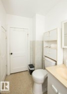 Bathroom featuring a built-in over-toilet storage unit, a single white vanity with an integrated sink, a wall-mounted mirror, and speckled flooring - 
