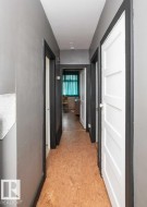 Hallway with light gray walls, dark trim, and cork-finish flooring - 