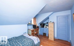 Room with sloped ceilings, hardwood-finish flooring, a window recess, and a paneled door with coordinating trim - 