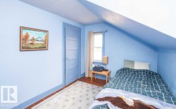 Room featuring wood-finish flooring, a paneled door, sloped ceiling detail, and a window with natural light - 