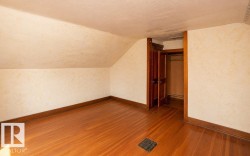 Room featuring sloped ceilings, wood-finish flooring, and a built-in closet with double bifold doors - 