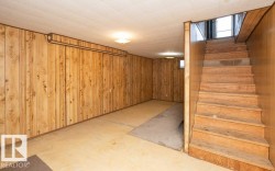 Finished basement space featuring extensive wood paneling and a drop ceiling - 