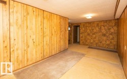 Room featuring wood-paneled walls, stone-patterned accent wall, and a textured ceiling - 