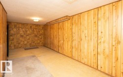 Room featuring wood paneling, a stone-patterned accent wall, and a textured ceiling - 