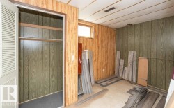 Room featuring wood-look paneling, a small window, and a built-in closet with louvered bi-fold doors - 