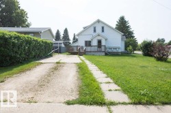 White-sided home featuring a wood deck with lattice skirting and a spacious front lawn - 
