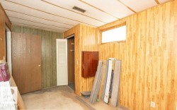Paneling-finished walls with a light wood-finish door and a window allowing ambient light - 