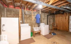 Basement utility area featuring exposed wood joists and concrete walls - 