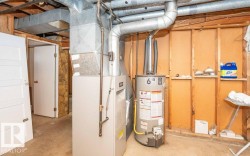 Utility area featuring a water heater and furnace with exposed ductwork - 