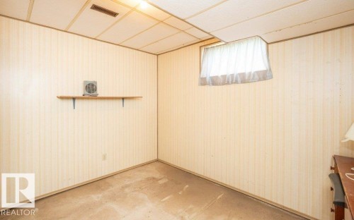 Room featuring light-toned striped wallpaper, drop ceiling with integrated ventilation, and a window with a sheer curtain - 10940 100A Ave, Westlock, AB - Indoor Photo Showing Other Room