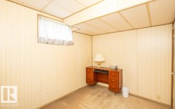 Finished room featuring light-toned paneling, a drop ceiling, and a window with white curtains - 