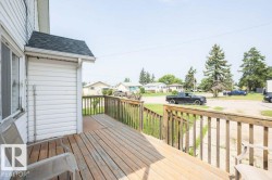 Expansive wooden deck featuring natural wood railings and siding with white vinyl siding - 