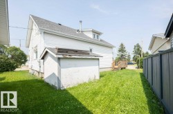 White siding exterior with a dark shingle roof and a ground-level shed - 
