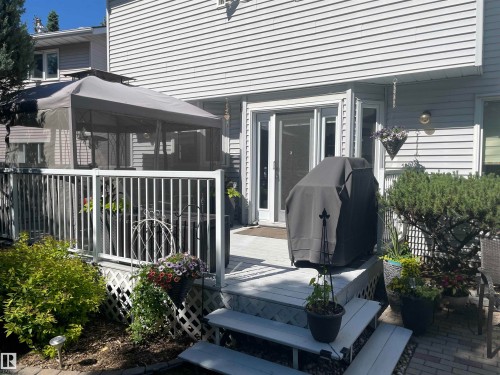 Rear deck featuring white painted wood, white railing, lattice skirting, and direct access through a glass-paneled door - 716 Hendra Crescent Nw, Edmonton, AB - Outdoor With Deck Patio Veranda