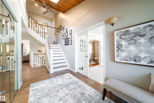 Two-story foyer featuring wood-finish flooring, white banisters with wood handrails, and a vaulted ceiling with a skylight and ceiling fan - 716 Hendra Crescent Nw, Edmonton, AB - Indoor Photo Showing Other Room