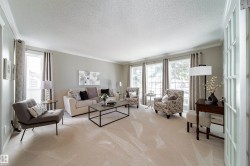 Spacious living area featuring light-colored wall paint, white crown molding, and plush carpeting - 