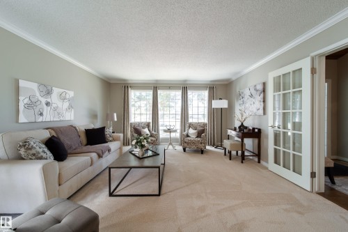Spacious kitchen featuring white cabinetry, stainless steel appliances, a center island with seating, a built-in wine refrigerator, and tile flooring - 716 Hendra Crescent Nw, Edmonton, AB - Indoor Photo Showing Living Room