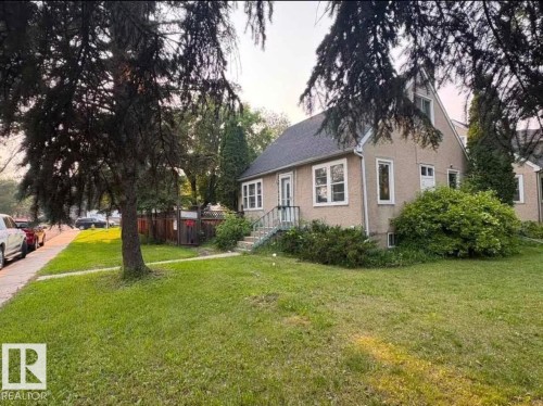 Stucco exterior, pitched roofline, multiple windows, established trees, and a concrete sidewalk - 10204 123 Avenue Nw, Edmonton, AB 