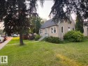 Stucco exterior, pitched roofline, multiple windows, established trees, and a concrete sidewalk - 10204 123 Avenue Nw, Edmonton, AB 