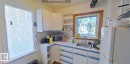 Corner kitchen with white cabinetry, stainless steel sink, and wood-framed window - 10204 123 Avenue Nw, Edmonton, AB 