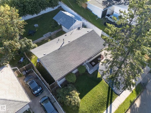 Gabled roofline with asphalt shingles, mature landscaping, paved driveway, and detached garage structure - 21 Sheridan Drive, St. Albert, AB 