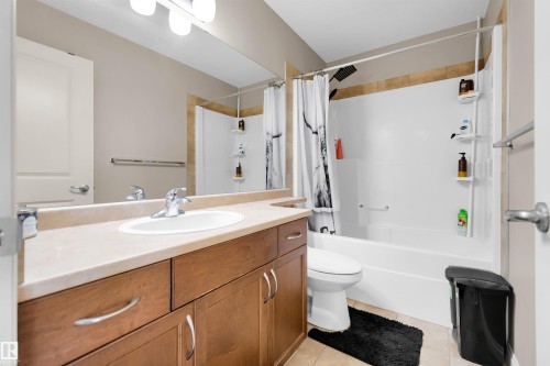 Warm wood-finish vanity with ample storage, single basin sink, and an expansive mirror - #5 5120 164 Av Nw, Edmonton, AB 