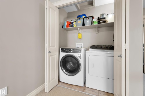 Dedicated laundry closet with full-size appliances and built-in shelving - #5 5120 164 Av Nw, Edmonton, AB 