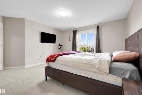 Wall-mounted television with shelving, light-colored carpet, and a window with a curtain rod - #5 5120 164 Av Nw, Edmonton, AB 