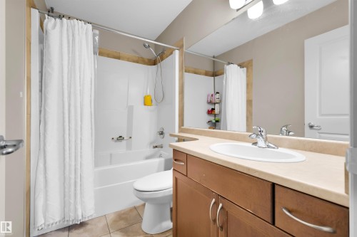 White drop-in bathtub with shower, wood-finish vanity with countertop, oval sink, and chrome faucet - #5 5120 164 Av Nw, Edmonton, AB 
