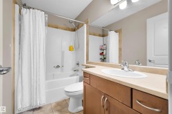 White drop-in bathtub with shower, wood-finish vanity with countertop, oval sink, and chrome faucet - 