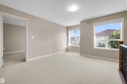 Carpeted flooring, neutral wall tones, multiple windows, overhead lighting, and built-in railing - 