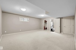 Spacious carpeted room featuring neutral wall tones, recessed lighting, a window with blinds, and white panel doors - 