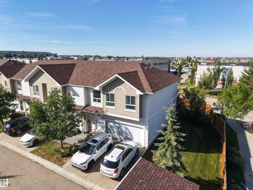 Two-story exterior with light-toned siding and a brown shingle roof - #5 5120 164 Av Nw, Edmonton, AB 