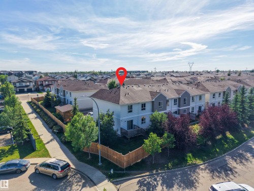 Residential property featuring a grey shingled roof, light-colored siding, and a wooden privacy fence - #5 5120 164 Av Nw, Edmonton, AB 