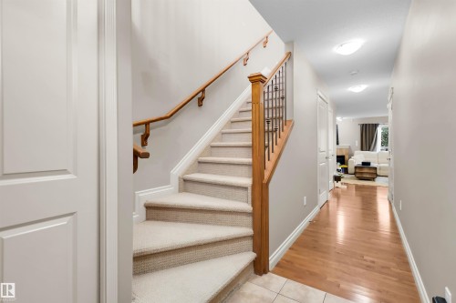 Carpeted staircase with wood banister and wrought iron spindles - #5 5120 164 Av Nw, Edmonton, AB 