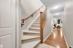 Carpeted staircase with wood banister and wrought iron spindles - 
