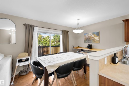 Wood-finish flooring throughout, sliding glass door with balcony access, pendant lighting fixture, and a built-in wood-finish countertop - #5 5120 164 Av Nw, Edmonton, AB 
