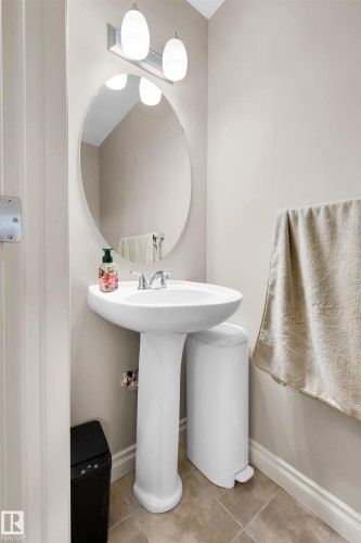 Pedestal sink with chrome faucet, oval mirror, and wall-mounted vanity light - #5 5120 164 Av Nw, Edmonton, AB 