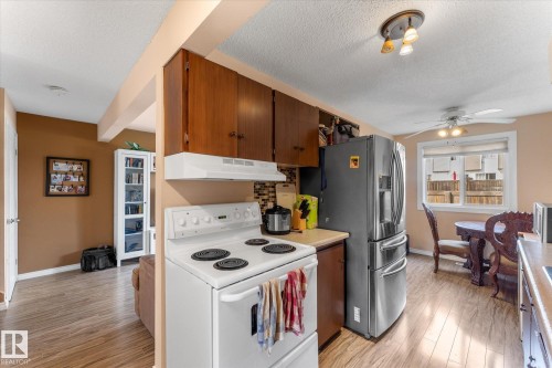 Kitchen featuring wood-finish flooring, white range, stainless steel refrigerator, wood cabinetry, and a tile backsplash - 173 Cornell Court Nw, Edmonton, AB - Indoor Photo Showing Kitchen