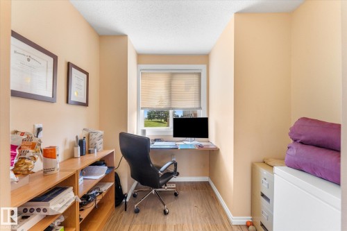 Compact space featuring light wood-finish flooring, a built-in window desk, and a window with horizontal blinds - 173 Cornell Court Nw, Edmonton, AB - Indoor Photo Showing Office